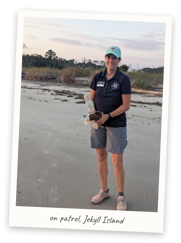 Polaroid photo: Lou Lou on the beach at Jekyll Island in her Georgia Sea Turtle Center uniform, collected debris in hand — captioned 'on patrol, Jekyll Island'