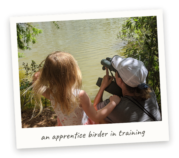 Polaroid photo: Lou Lou birding at the pond with binoculars, her granddaughter beside her — captioned 'an apprentice birder in training'